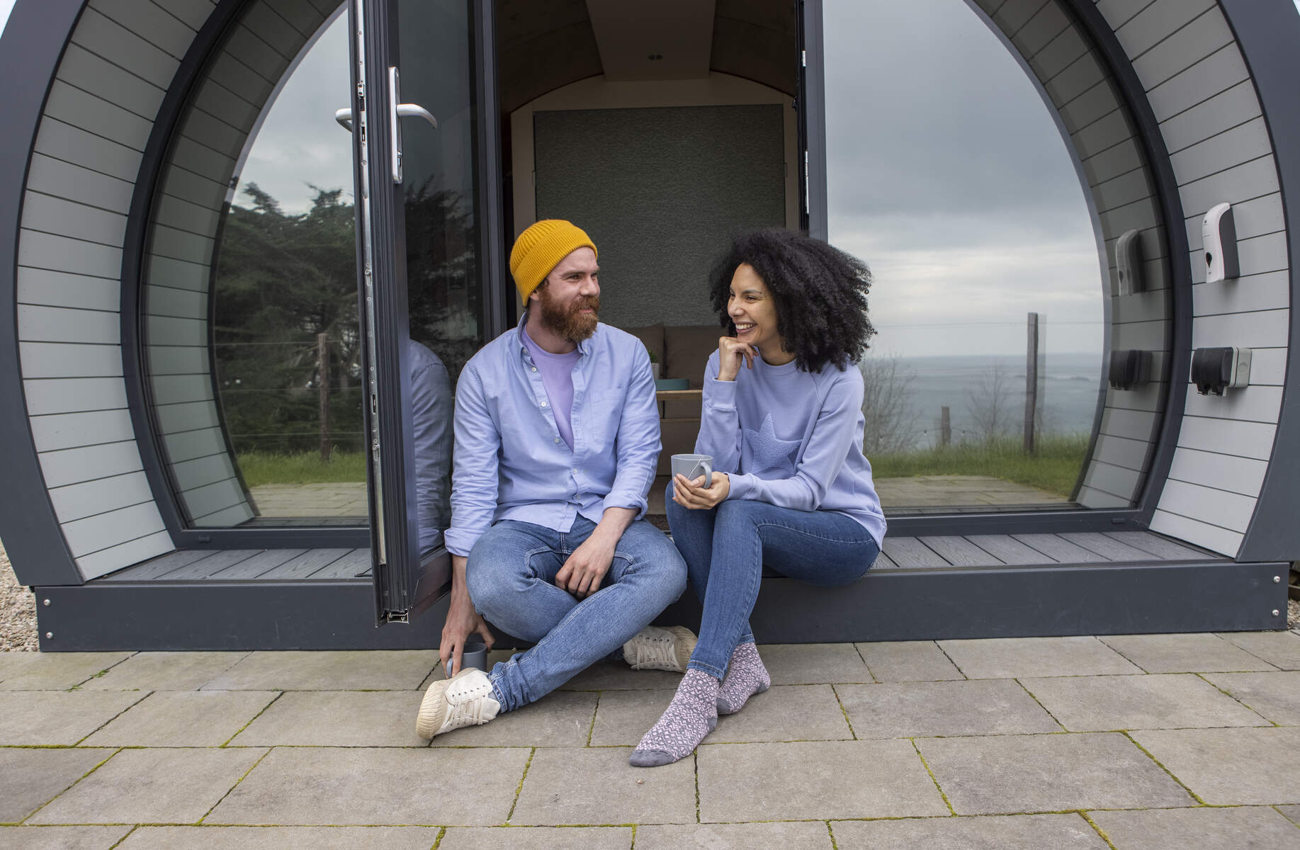 Couple sitting out the front of their glamping pod