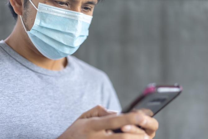Young man wear protective masks for safety and prevention of COVID-19 and are using a smartphone